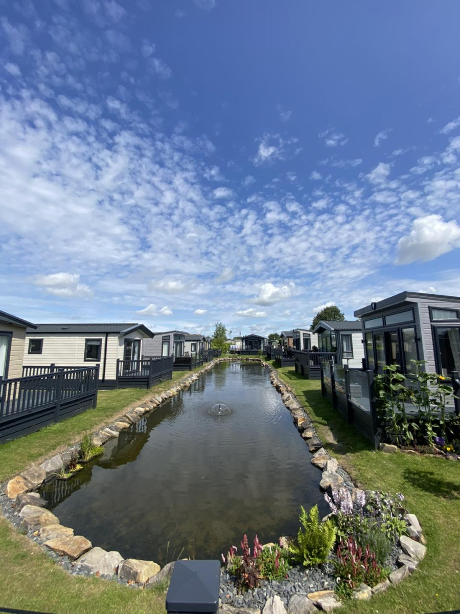 A tranquil view of the Lytham Edge community with modern homes alongside a gentle waterway under a beautiful sky.